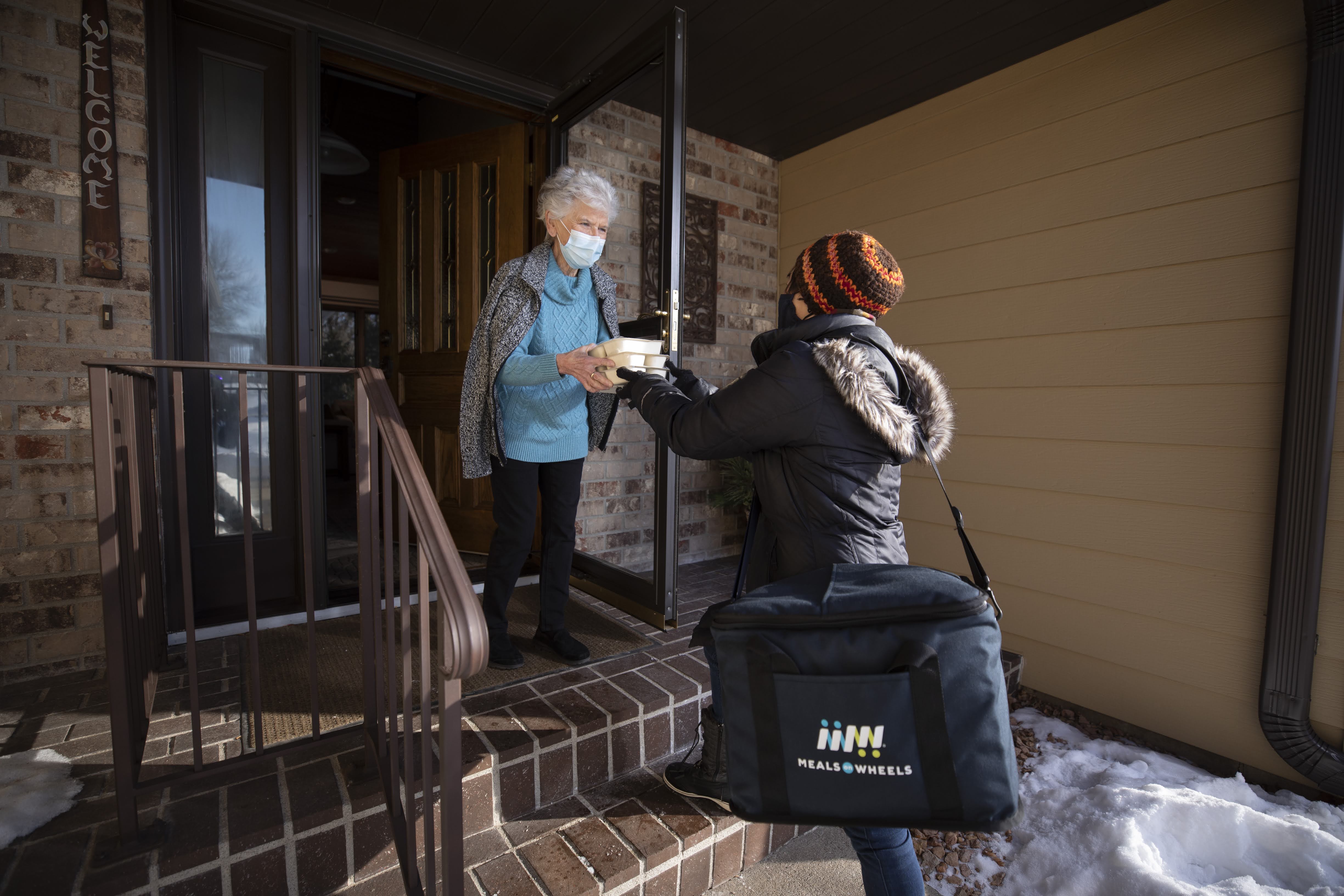 Volunteer handing meal to Meals on Wheels client