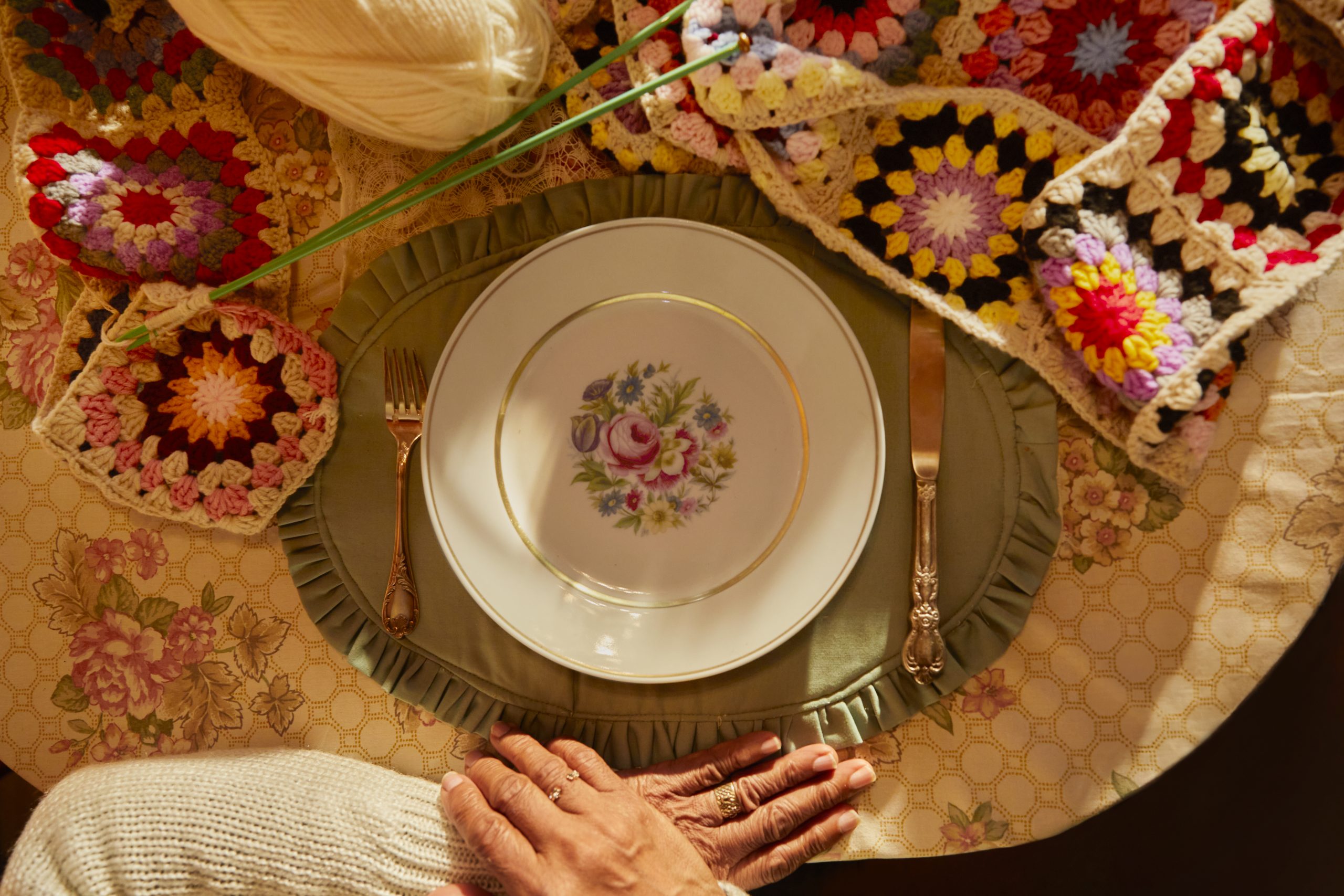 Woman waiting in front of an empty dinner plate with a very long knitted scarf