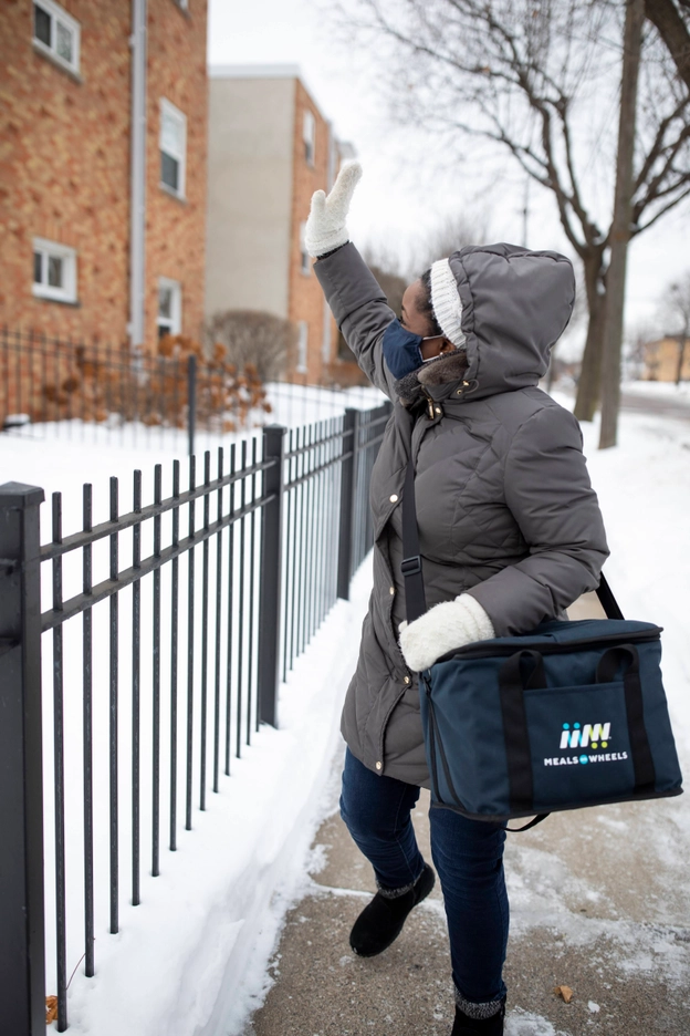 Black Female Volunteer Gray Jacket Delivering Meals and Waving 02