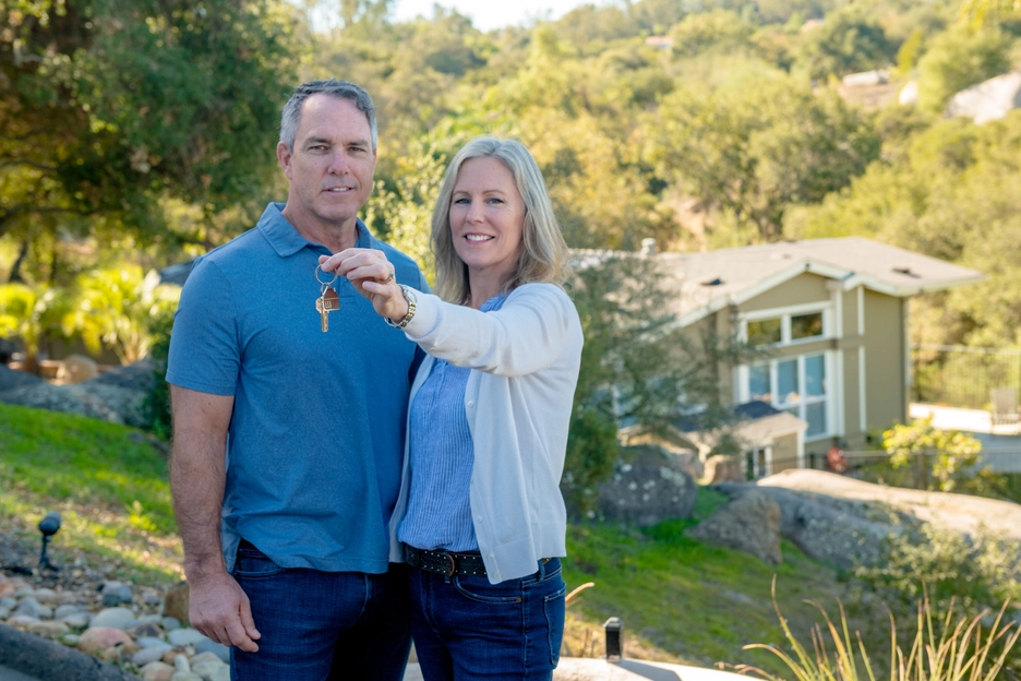 White Couple Holding Car Keys with New Car Outside