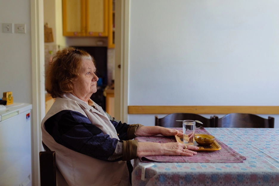 White Female Client White Vest Staring Sadly from Kitchen Table - Hunger and Malnutrition