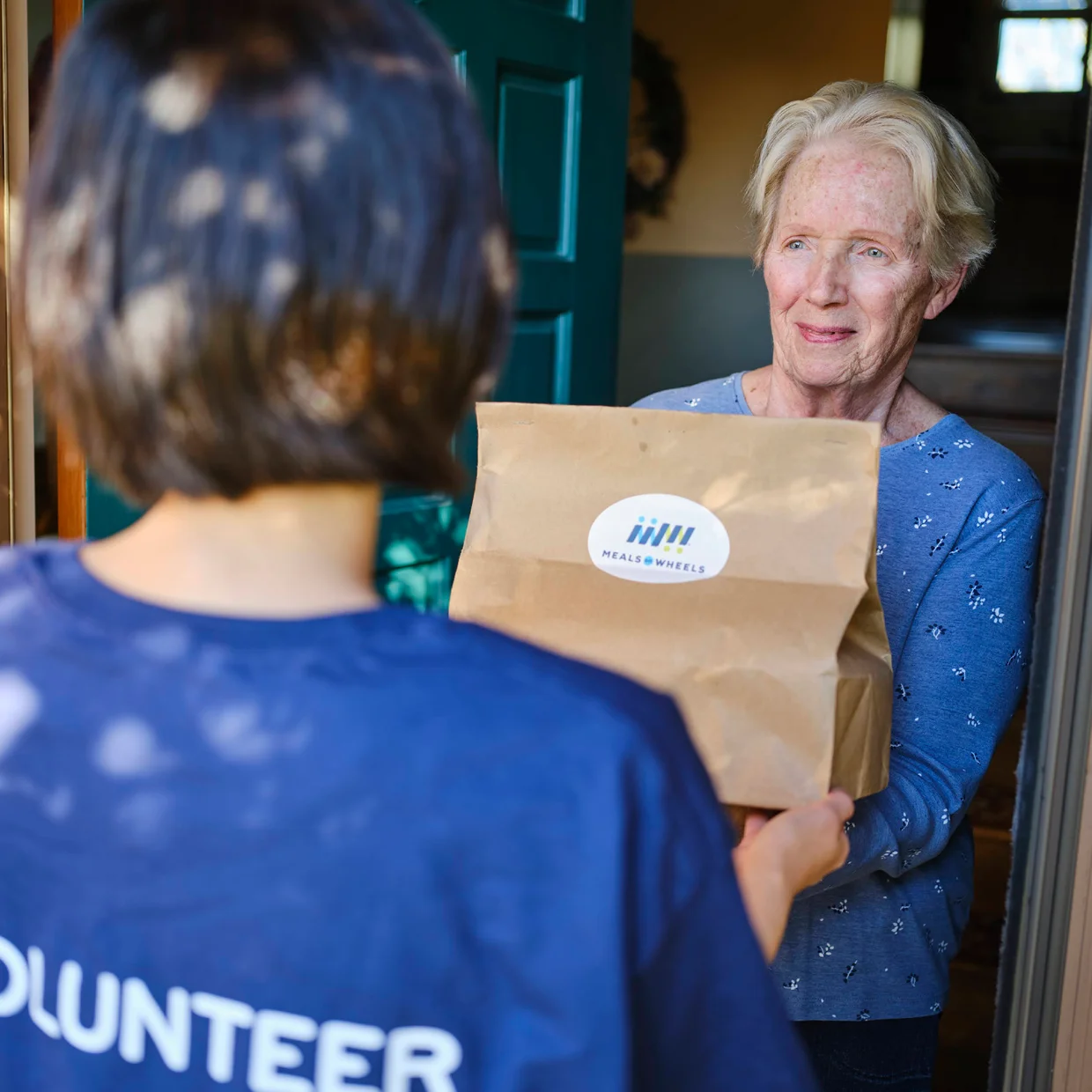 White Female Client accepting meal from Volunteer