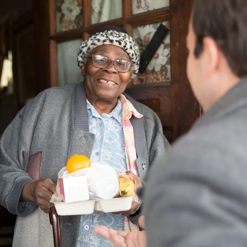 White Male Volunteer with Black Female Client Delivering Meal at Door Happy - Meals on Wheels Research - Facts and Data