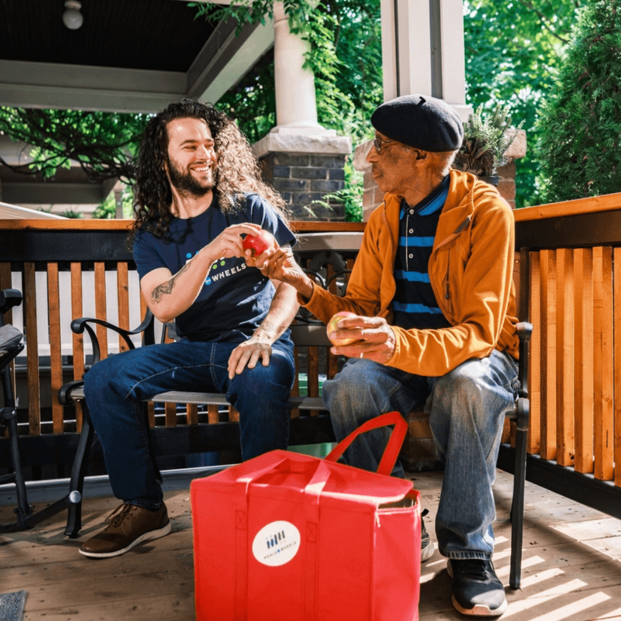 White Male Volunteer with Black Male Client Bonding on Porch with Meal Delivery Bag Branded (1)