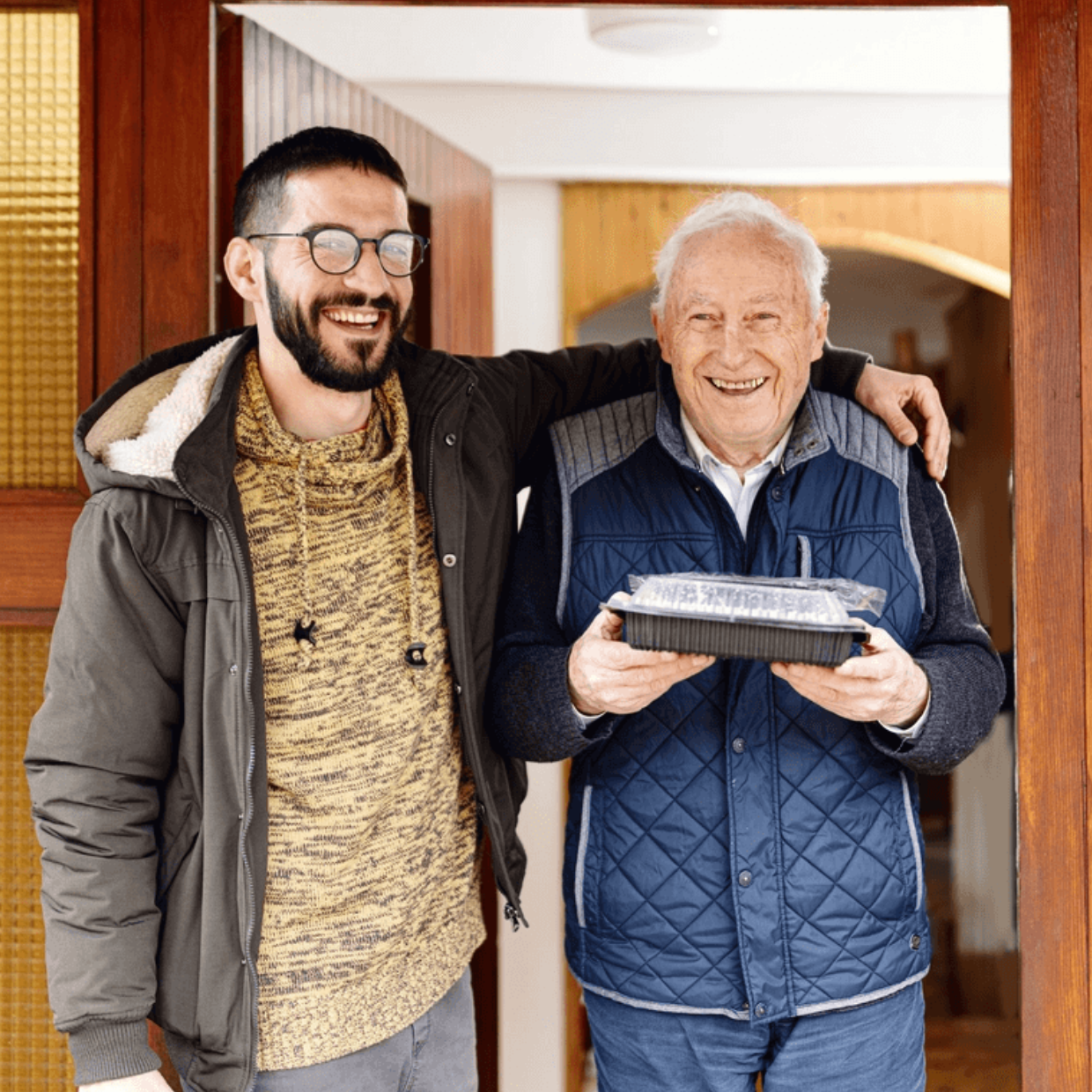 White Male Volunteer with White Male Client At Door Smiling with Meal Delivery