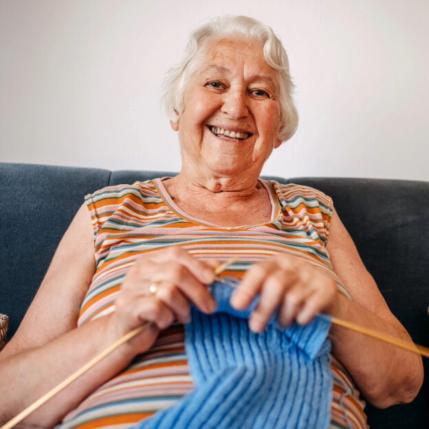 White Female Happily Knitting - Meals on Wheels Work Addressing Social Isolation