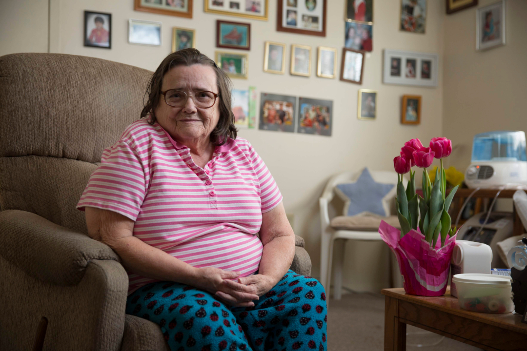 Woman Sitting in Chair with Family Photos Behind Her
