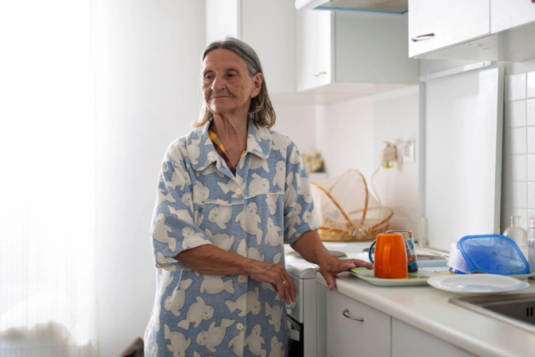 White Female Client Standing in Kitchen - senior economic hardship