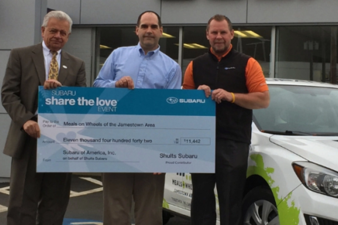 Three men hold Subaru Share the Love check - community partnerships