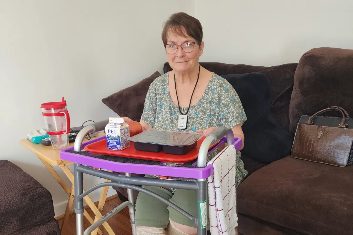 Cameron Hartwell Davidson smiling while sitting on couch with meal in front of her.