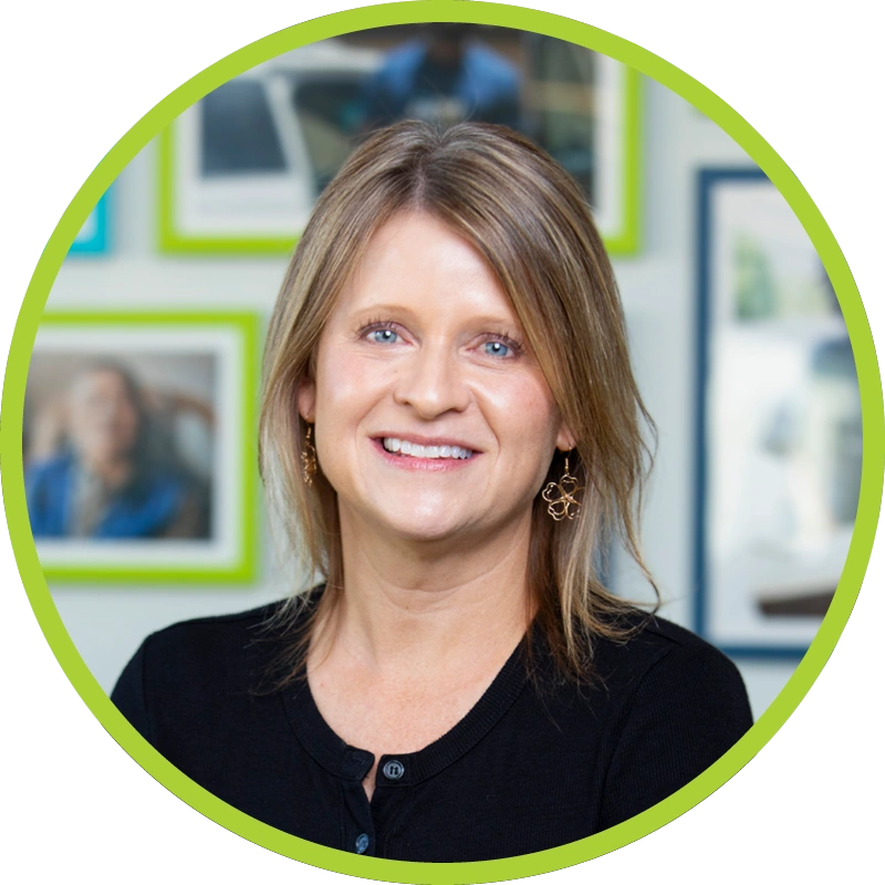Kelly Trimyer smiling wearing black button-down cardigan and gold earrings.