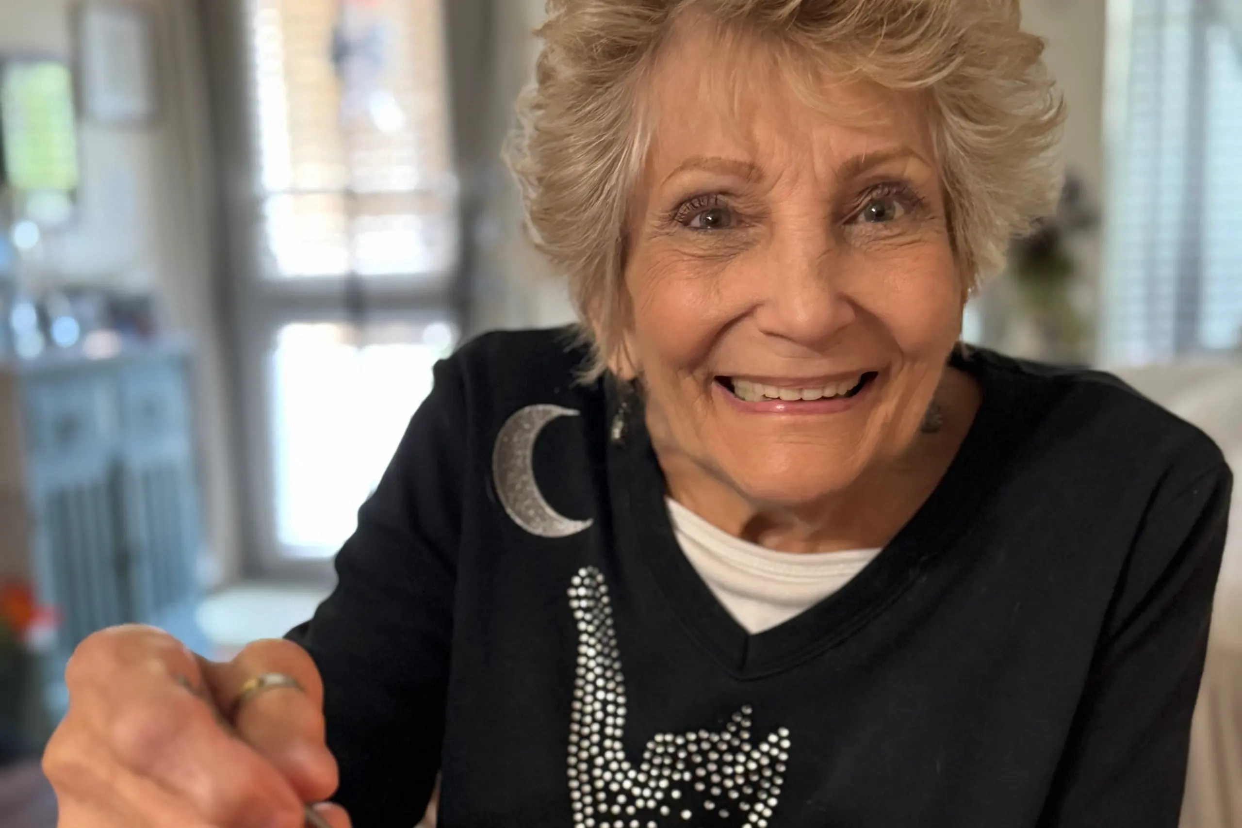 Mildred smiling wearing a black top with silver accents.
