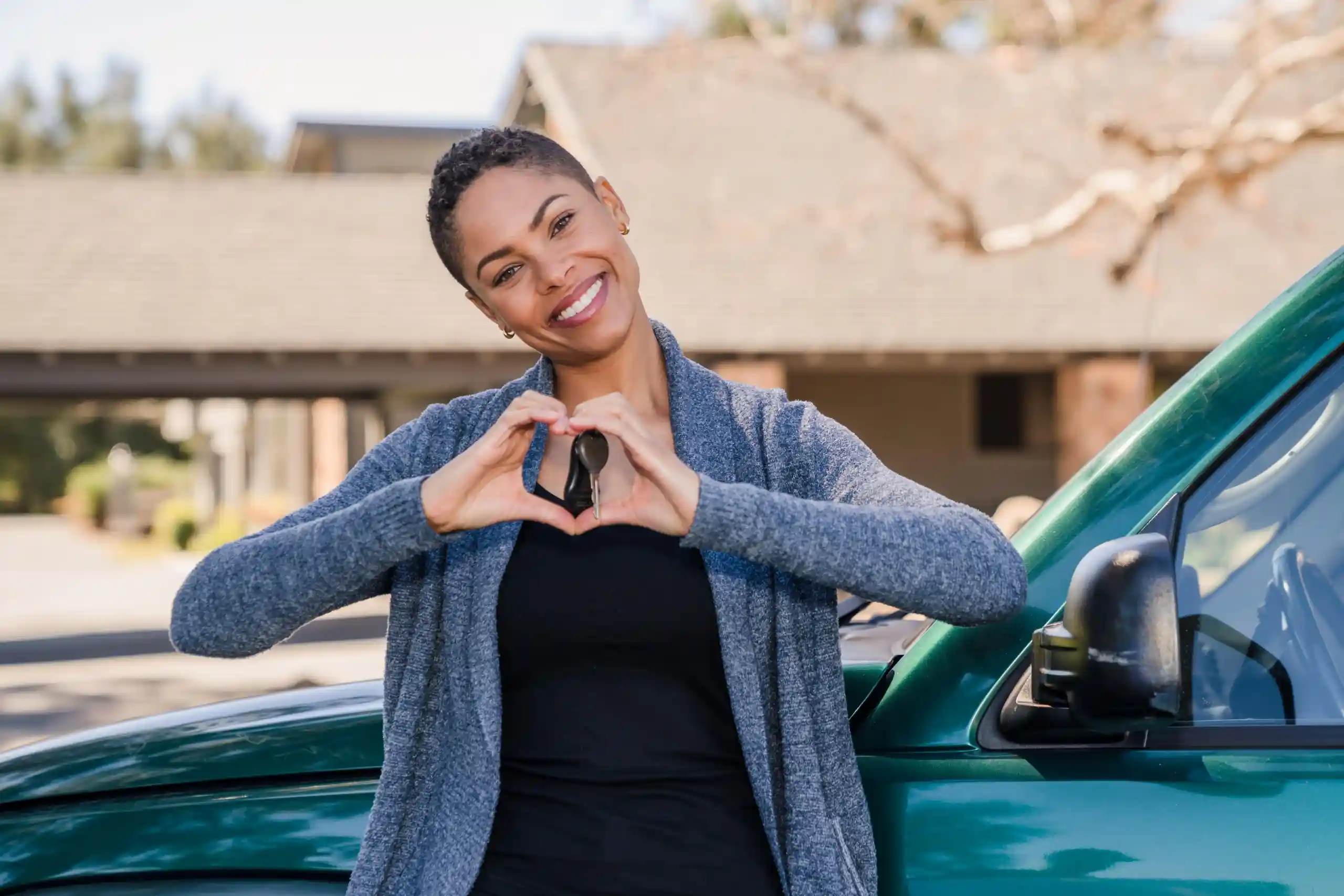 Woman with car keys and house in background.