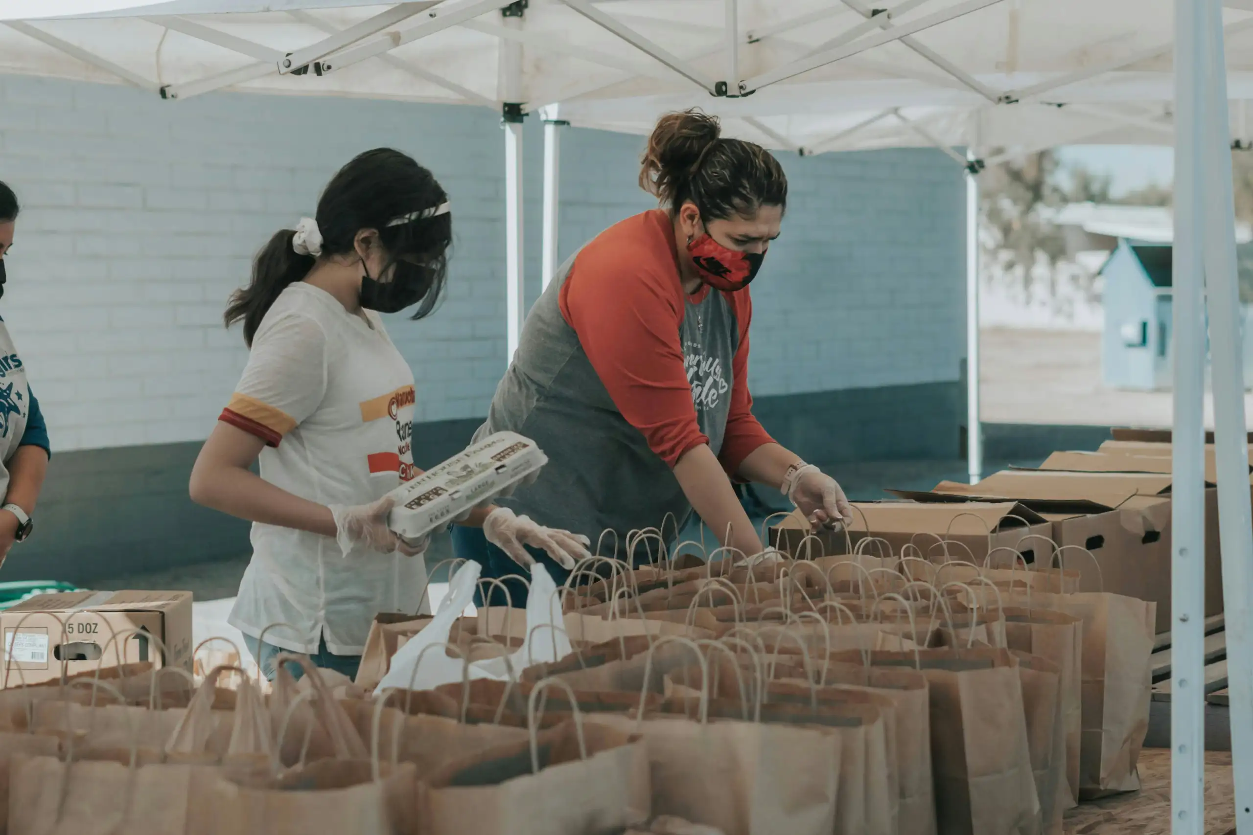 Meals on Wheels volunteers packing meals in brown bags.