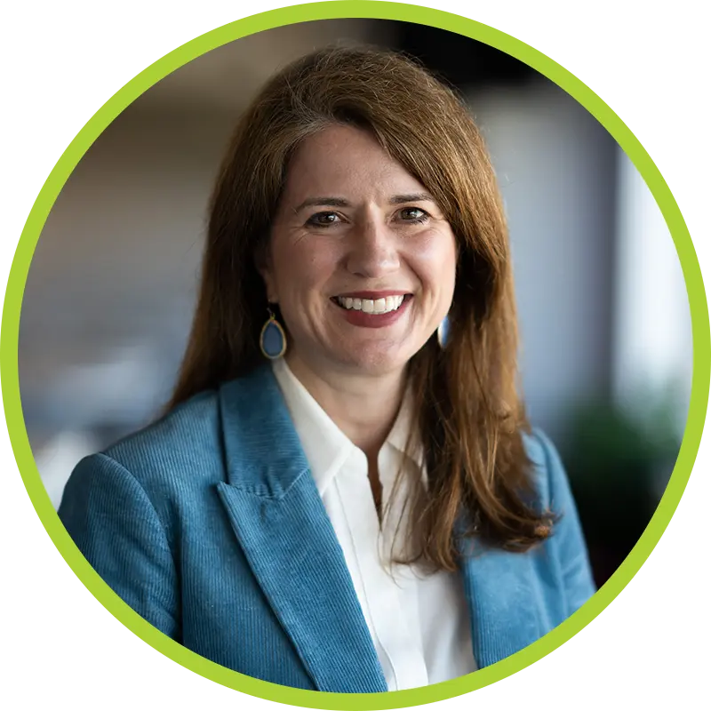 Jennifer Allen smiling wearing blue earrings, a teal blazer, and a white button down top.