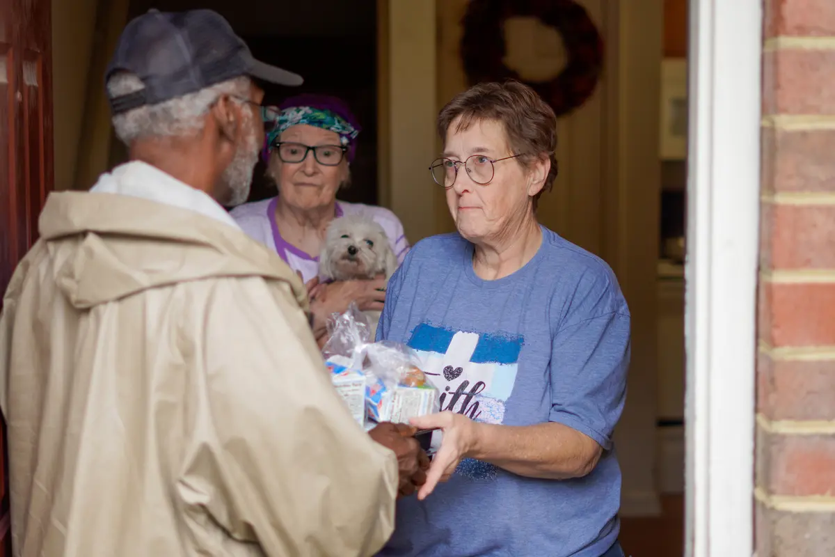 Terry Samm-Garris and Gloria Franklin at the entrance of their home with a Meals on Wheels volunteer.