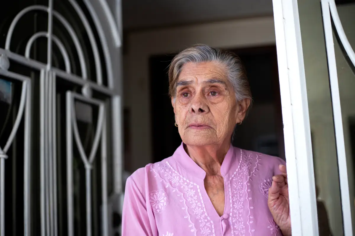 Senior woman standing in door alone looking ahead.