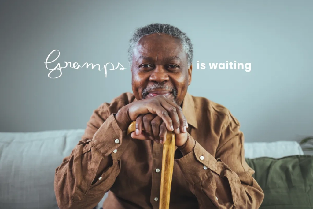 Black male senior sitting on couch smiling with the words "Gramps in waiting"