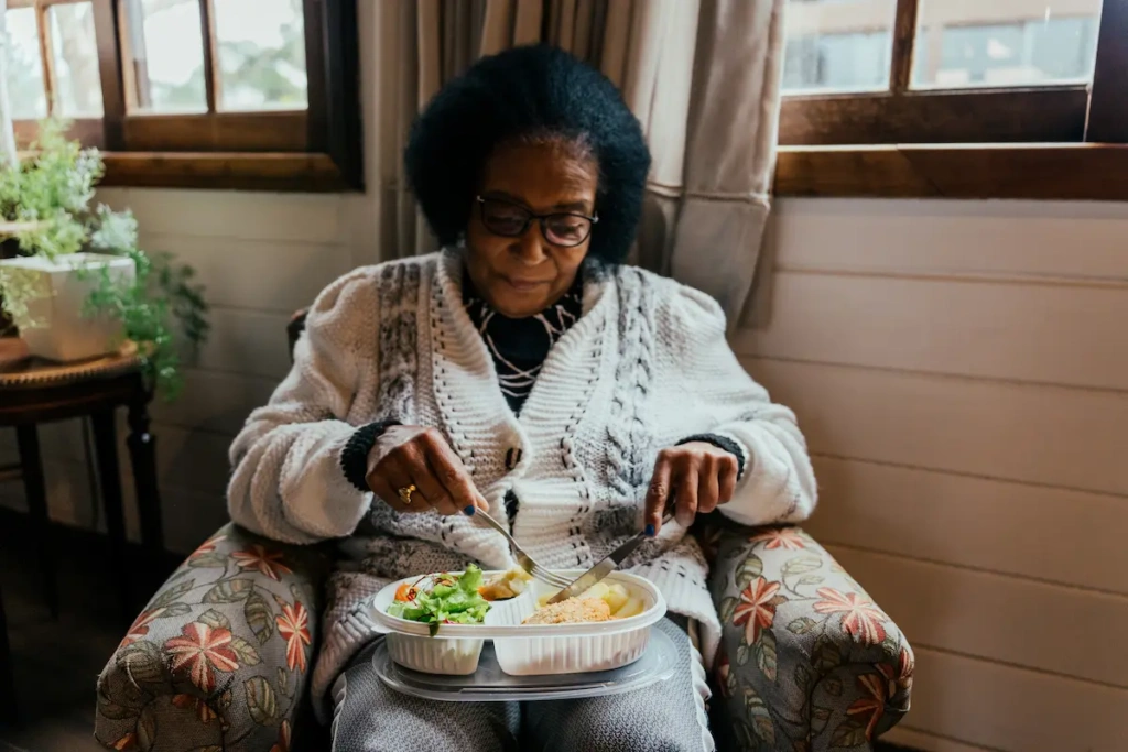 Black Female Client Eating Meal in Armchair
