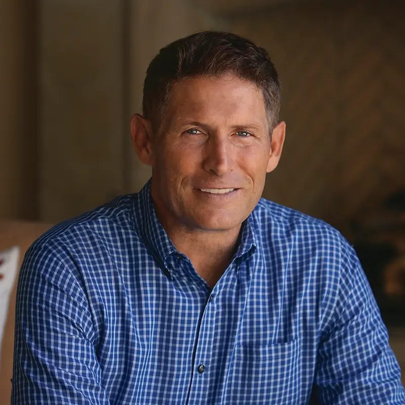 Steven Young smiling while wearing blue and white plaid shirt.