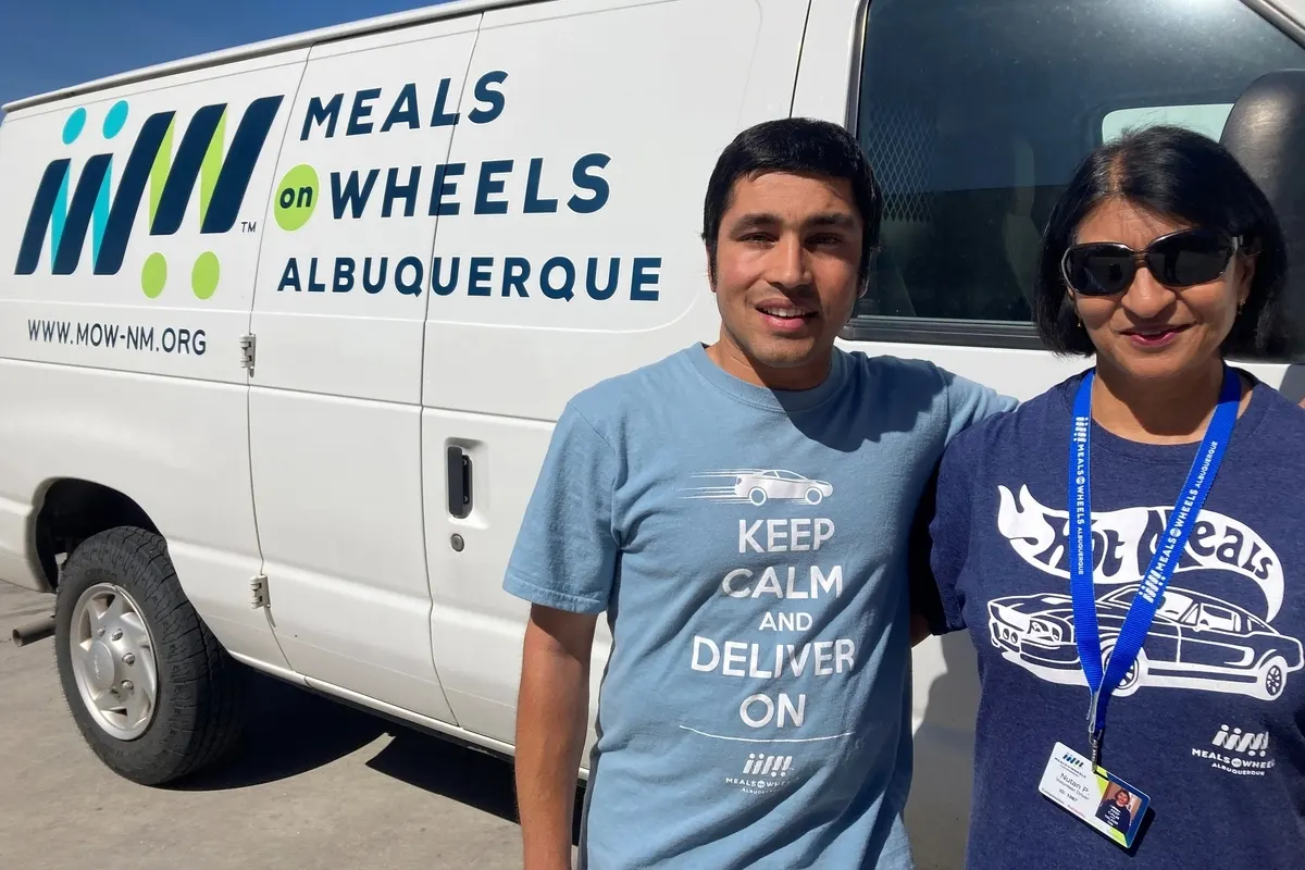Nutan and her son in front of a Meals on Wheels Albuquerque van.